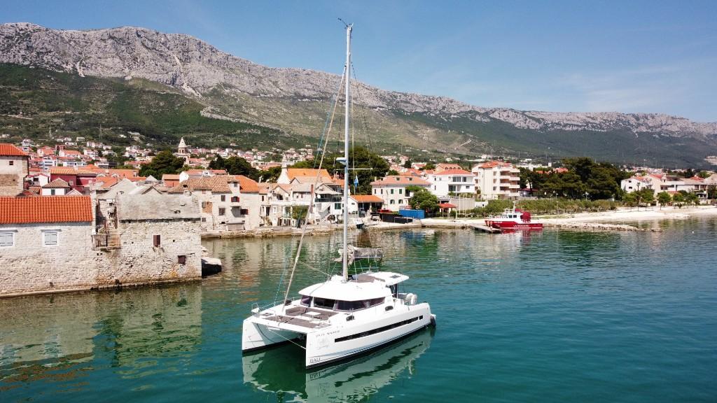 Catamaran au mouillage face à un village méditerranéen, destination GlobeSailor